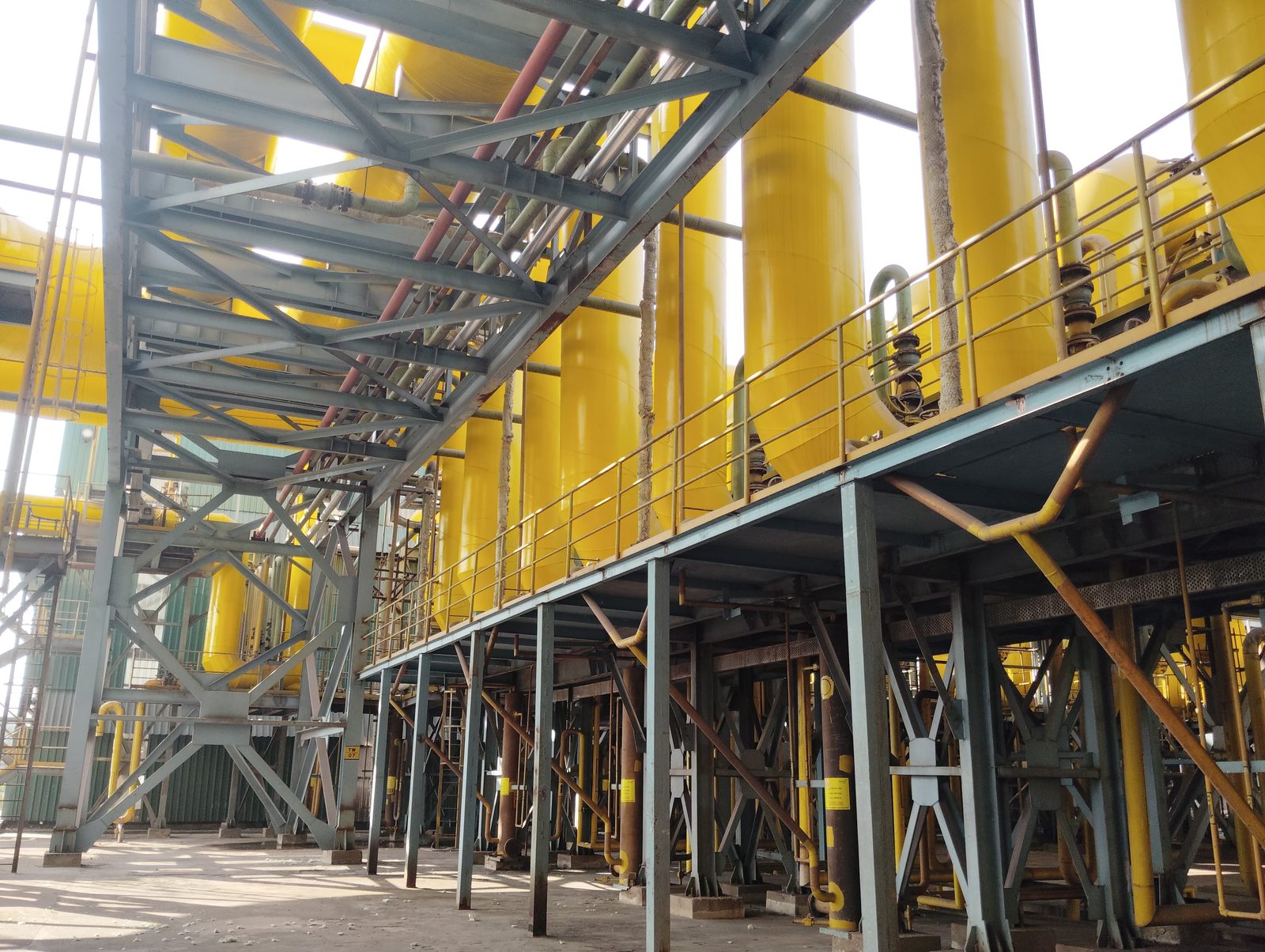 Yellow-coated reactor columns and process vessels with steel access walkway at an industrial plant